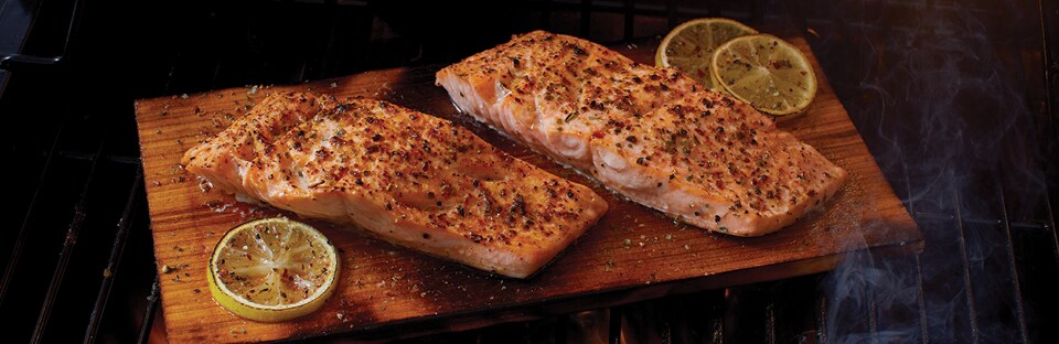 Salmon filets on wood plank on grill