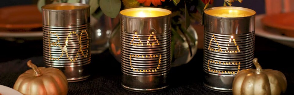 Three punched tin cans with tealights inside