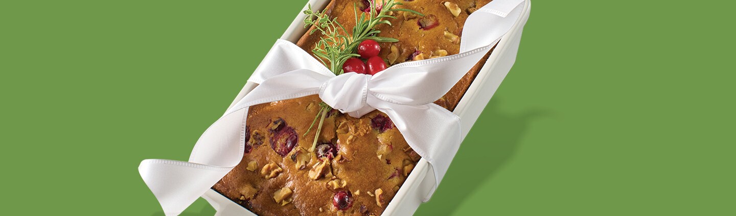 vegan cranberry bread recipe baked in a white bread pan wrapped in a ribbon