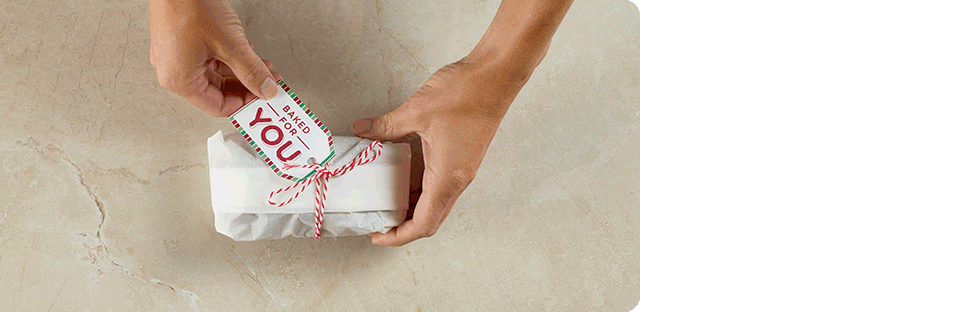 steps showing someone wrapping a loaf of sweet bread in parchment paper and tying with a ribbon and gift tag
