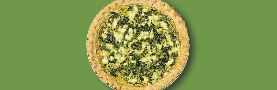A single spinach and feta quiche on a green background.