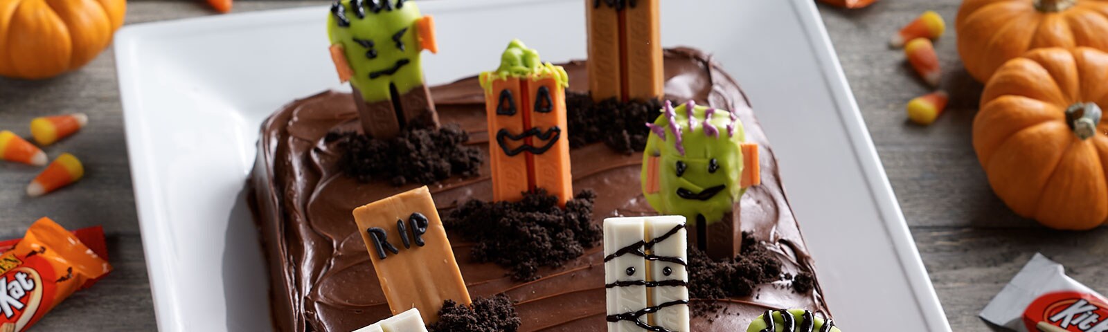 Chocolate cake with Halloween-themed Kit Kat bars placed on top to resemble a spooky graveyard