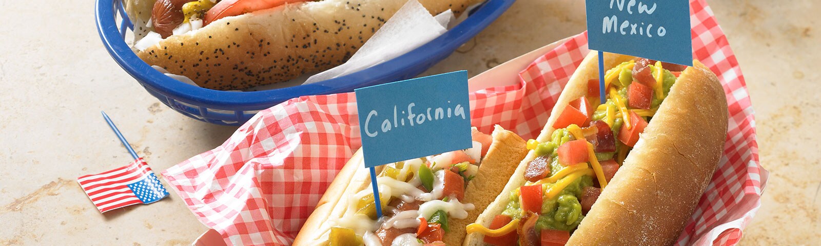 Chicago, New Mexico and California-style hot dogs with pickle relish, tomato slices and shredded cheeses as toppings Chicago, New Mexico and California-style hot dogs with pickle relish, tomato slices and shredded cheeses as toppings