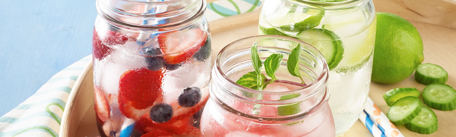 Mason jars filled with water, ice cubes and berries sitting on a tray Mason jars filled with water, ice cubes and berries sitting on a tray