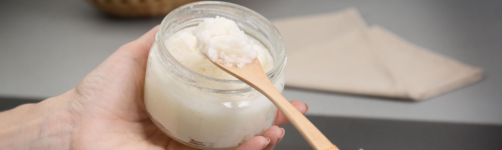 A pair of hands scooping coconut oil from a jar A pair of hands scooping coconut oil from a jar