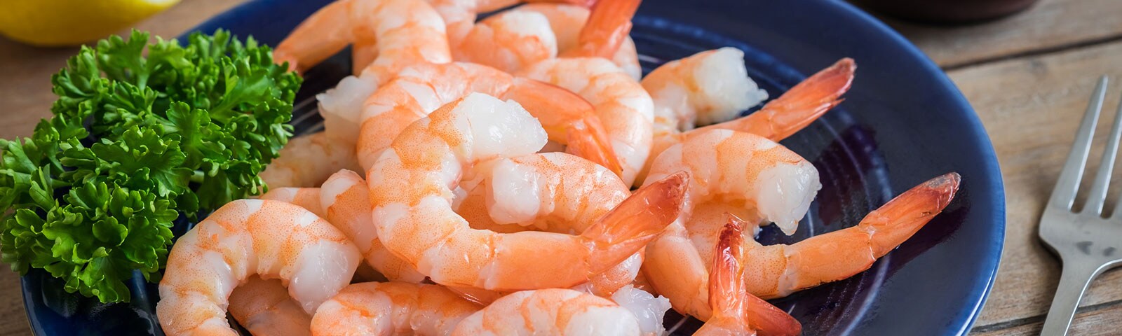 Shrimp with lettuce on a blue plate on a wooden table Shrimp with lettuce on a blue plate on a wooden table