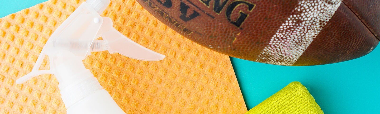 A dish towel, a football, and a spray bottle sitting on a blue background