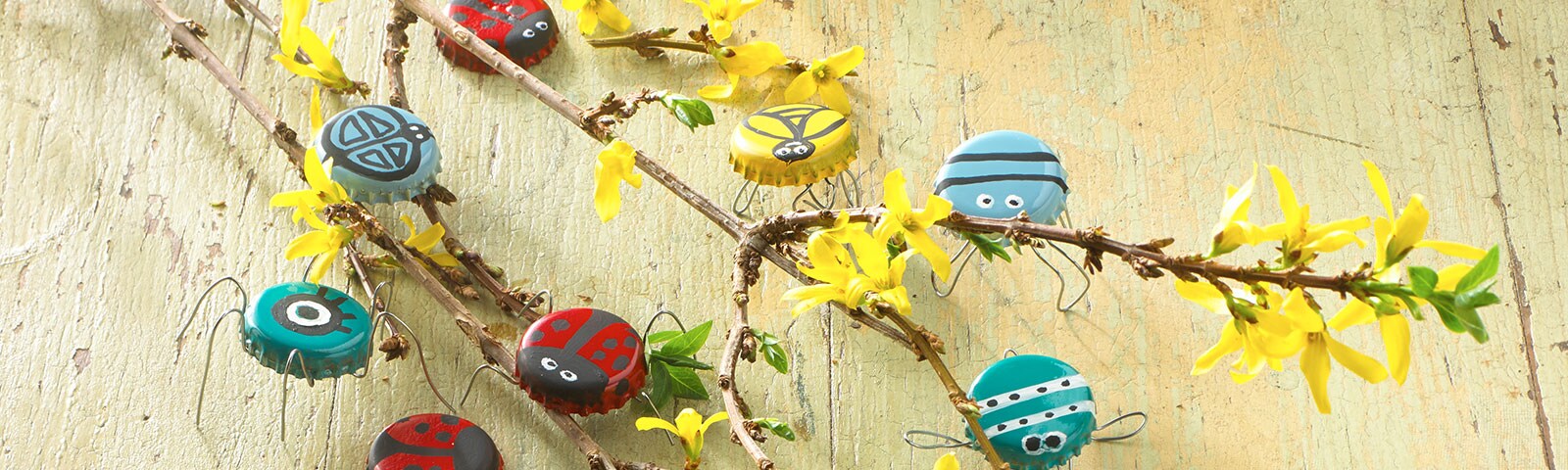 Lady bug and spider painted bottle caps attached to a thin tree branch Lady bug and spider painted bottle caps attached to a thin tree branch
