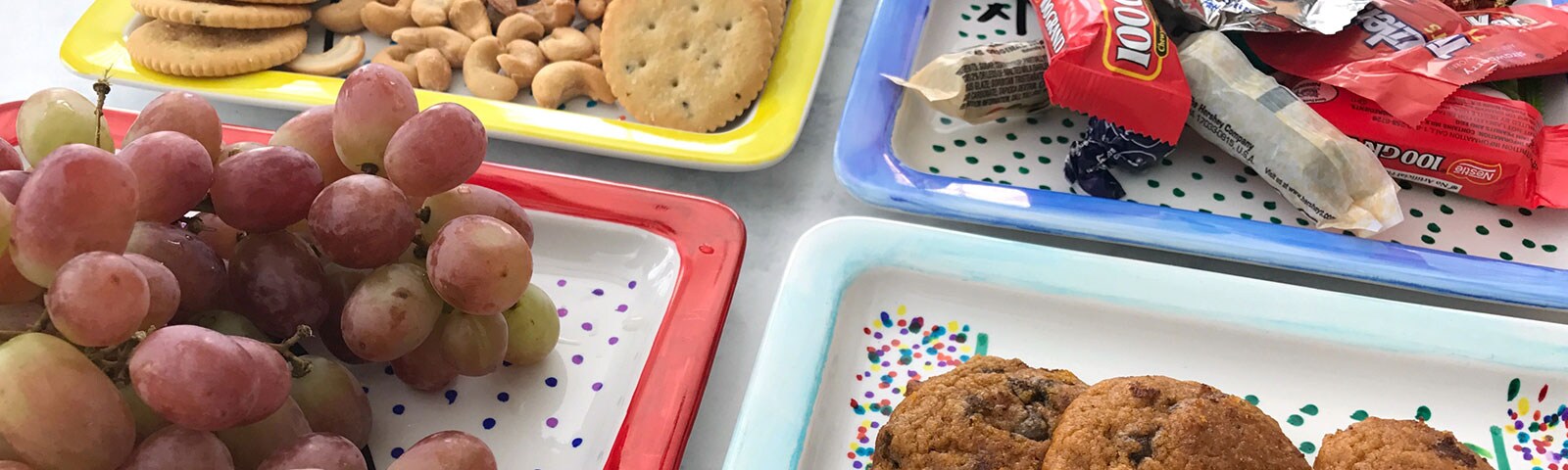 Decorated porcelain plates with a colorful polka dot design each filled with game day treats like grapes, crackers, cookies and candy Decorated porcelain plates with a colorful polka dot design each filled with game day treats like grapes, crackers, cookies and candy