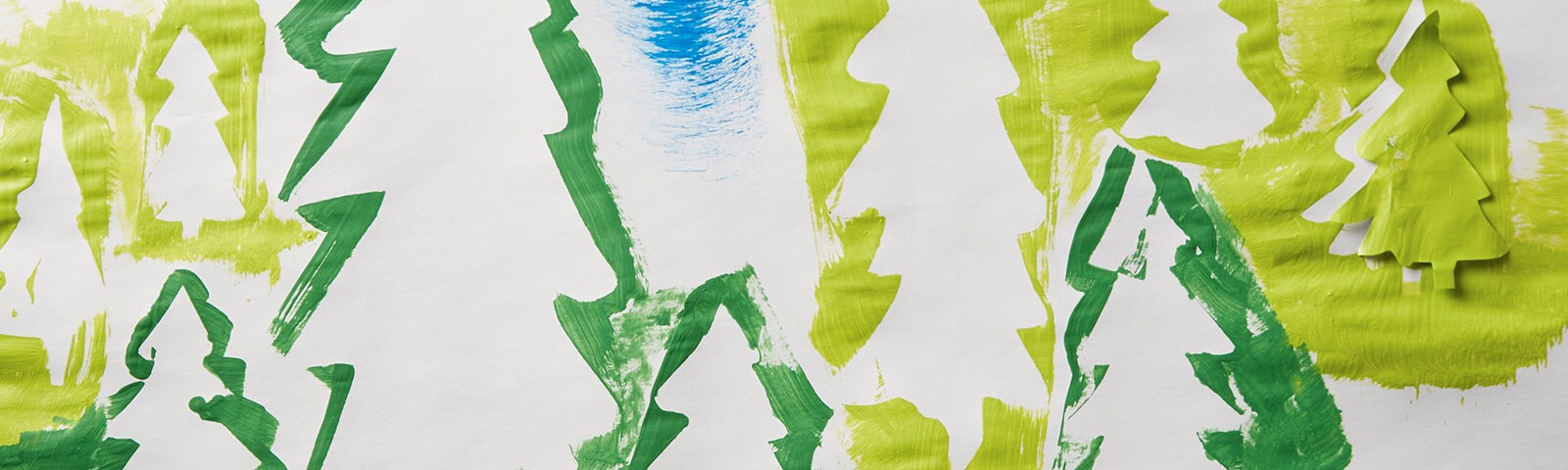A long, horizontal piece of white paper covered in tree silhouettes of various sizes and shades of green
