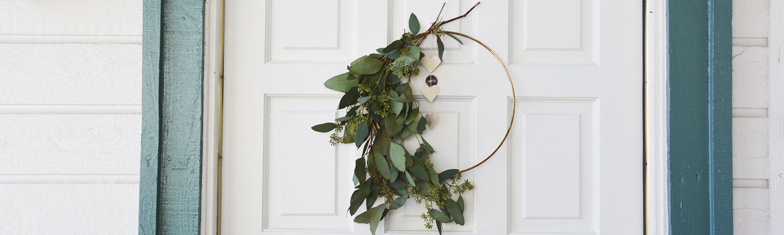 A white door with a handcrafted eucalyptus wreath hanging in the center A white door with a handcrafted eucalyptus wreath hanging in the center