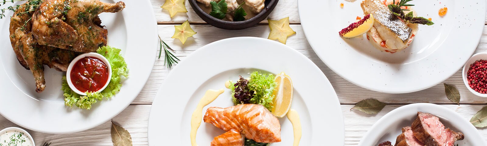 A table covered in various delicious dishes, from a roasted chicken to grilled salmon A table covered in various delicious dishes, from a roasted chicken to grilled salmon