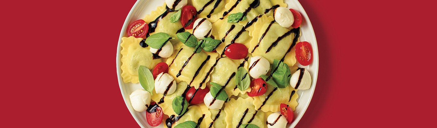 Ravioli with fresh tomatoes, mozzarella, and basil, drizzled with balsamic glaze